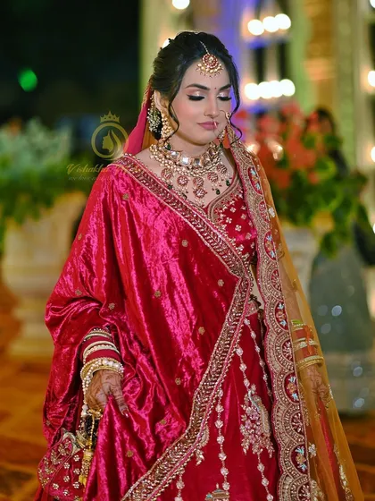 This full-length view shows how a grand jewellery set can define the entire bridal look. The bride is wearing a heavy kundan polki necklace that perfectly complements the rich texture and color of her velvet lehenga.