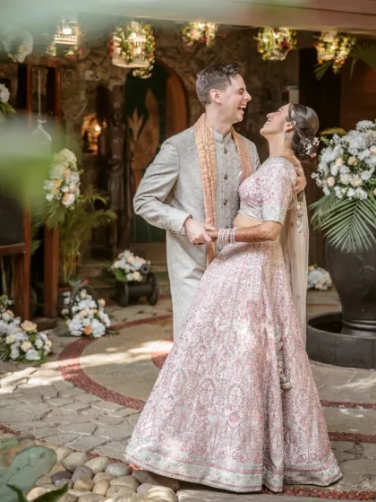 A moment of pure, unscripted laughter between the bride and groom in a beautiful courtyard setting on their wedding day.