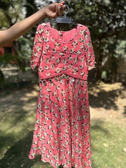 This pink floral dress with a mirror-work belt is a perfect blend of comfort and style. The flowy fabric and bright print make it an ideal choice for a summer wedding or party.