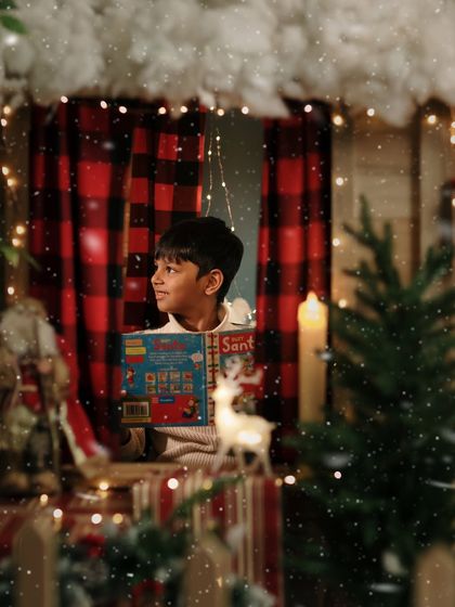 A magical portrait of a boy looking out the cabin window as snow falls.