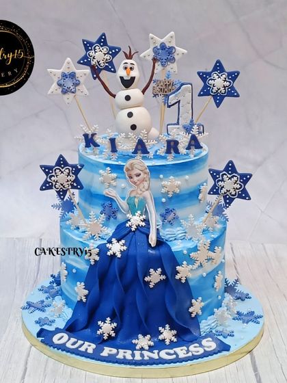 A stunning two-tier Frozen-themed cake. This 3kg pineapple cake features a fondant Elsa, Olaf, and intricate snowflake decorations, creating a winter wonderland for a first birthday.