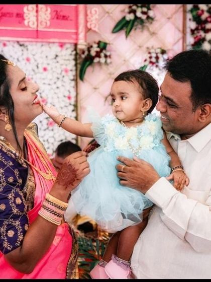 A precious family moment from the naming ceremony, with the baby girl reaching out to touch her mother's face as her father holds her.