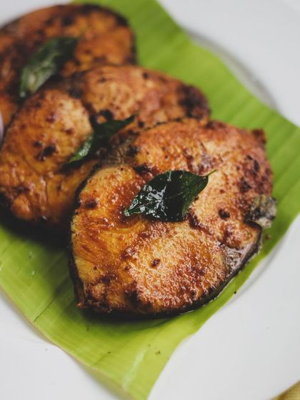 Pan-fried fish steaks, seasoned with Indian spices and served on a banana leaf. A simple, flavorful dish that highlights the beauty of coastal Indian cuisine.