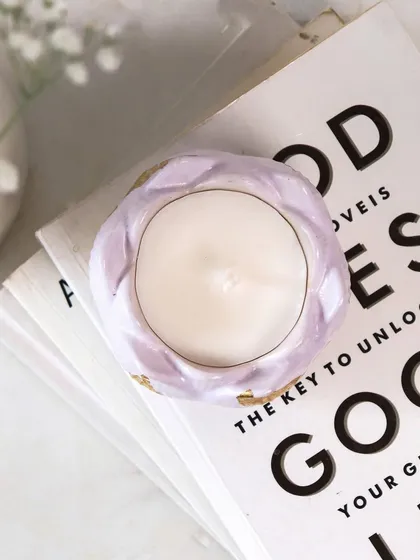 Our lilac Lotus Jar candle resting on a stack of books. It's the perfect little piece to create a cozy and warm atmosphere for the festive season.