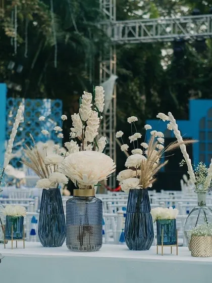 A centerpiece detail from the 'Bar Palladio' Haldi, featuring sholawood flowers in blue glass vases, creating a beautiful contrast of color and texture.