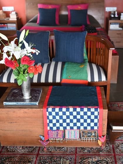 The Lambani-edged throw styled on a bench, showing its versatility as a decorative accent. The checkered pattern and coin details of the Lambani patches add a distinct tribal touch.