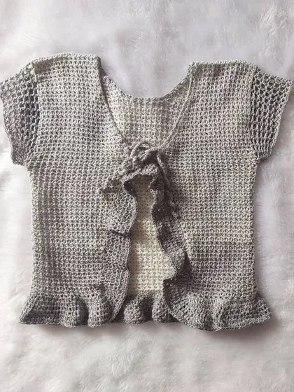 A flat-lay of the Orchid Top, showcasing the front tie and ruffled details.