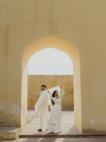 A playful and artistic pose using a sheer dupatta against the sunlit arches of Jaipur. We love incorporating creative elements to make your pre-wedding photos unique.