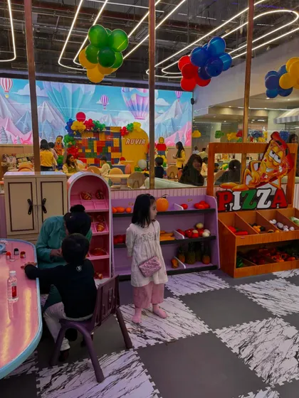 A wide view of our play area, showing the pretend play market, creative tables, and a birthday party setup in the background.