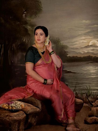 A beautiful artistic portrait inspired by classic Indian paintings. The mother-to-be, in a pink saree, sits by a painted moonlit river, creating a serene and timeless scene.