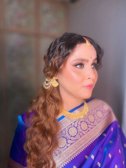 A side profile, highlighting the soft curls in her hair and the flawless finish of her makeup.