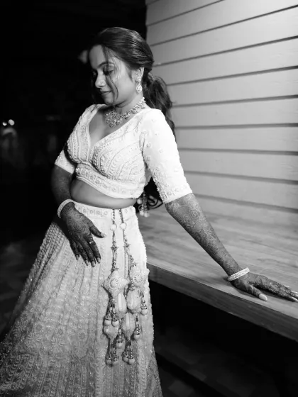 A dramatic black and white photo, showcasing the silhouette of the lehenga and the bride's pose.