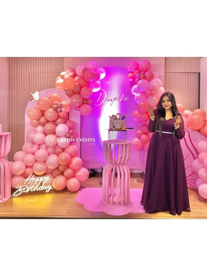 The birthday girl enjoying her pretty-in-pink butterfly-themed party. The shades of pink balloons and custom name sign create a perfect photo backdrop.