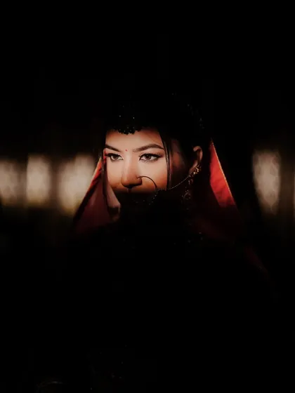 An artistic and mysterious portrait of the bride, her face partially lit, highlighting her beautiful eyes and nose ring.