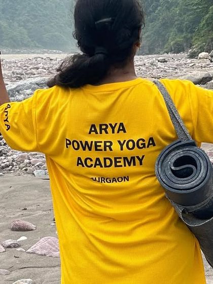Ready for practice. A student stands on the banks of the Ganges, mat in hand, embracing the peace and energy of Rishikesh.