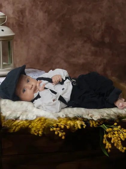 A vintage-style portrait of a baby boy dressed in a classic outfit with a newsboy cap. I use props like this antique-style lantern to add character to the photos.