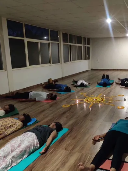 Participants resting in Savasana during a sound healing workshop, surrounded by a candlelit mandala. This state of deep rest allows the healing vibrations to integrate fully.