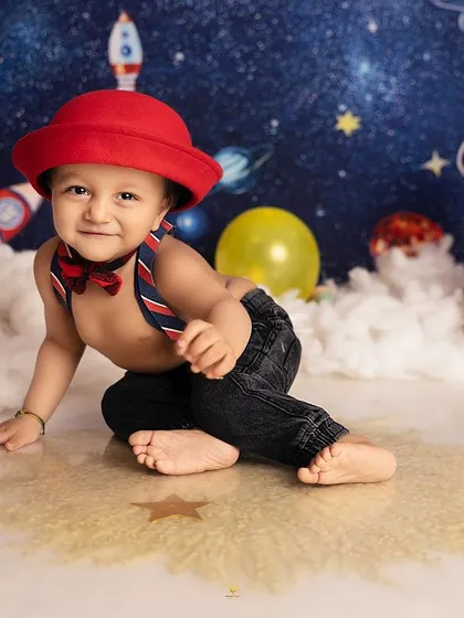 This little space explorer is ready for his close-up. The bright red hat adds a pop of color to the galactic backdrop, and his expression is simply out of this world.