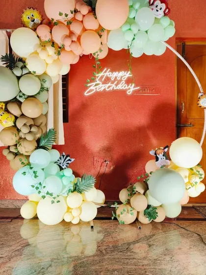 Another angle of the pastel jungle balloon ring with a 'Happy Birthday' neon sign.