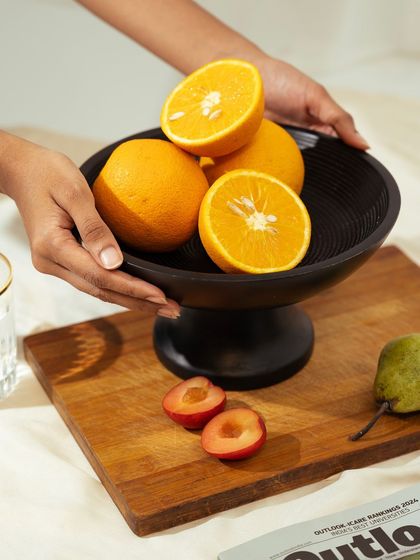 A lifestyle shot of hands holding the fruit bowl, with a wooden board and other elements in the scene. This adds a human touch and context.
