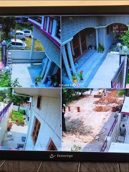 A clear 4-camera view showing the exterior of a house, including the street and construction work nearby.