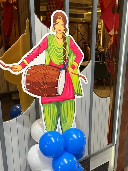 A traditional Punjabi dhol player cutout adds an authentic touch to the Lohri party decor.