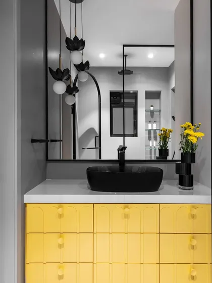 A closer look at the yellow vanity and the unique pendant lights. The contrast between the vibrant yellow, the matte black, and the grey walls creates a dynamic and stylish bathroom design.