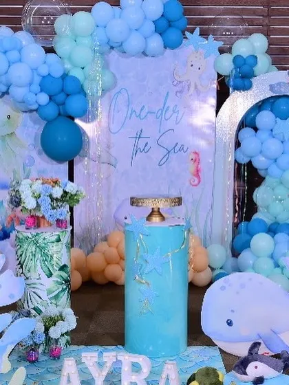 The central part of the backdrop, with the 'One-der the Sea' sign, a cake plinth decorated with starfish, and cute whale and octopus cutouts.
