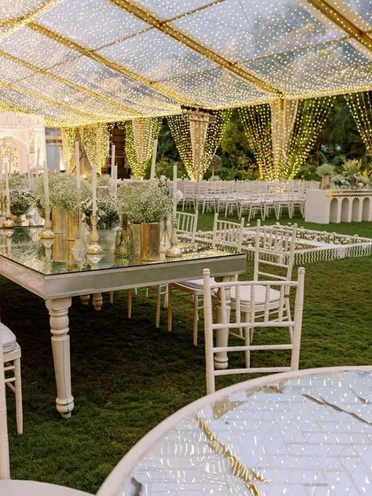 The elegant dining setup under the starlit tent. The long, mirrored tables and white Chiavari chairs create a sophisticated and cohesive look.