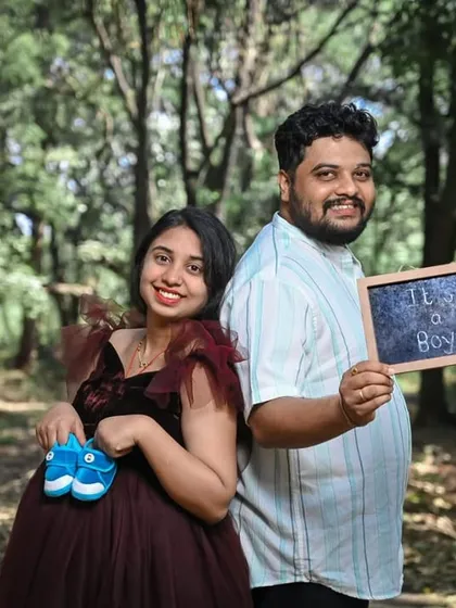 Celebrating with cute props like baby shoes. This couple's maternity shoot is made even more special, with the mom-to-be looking radiant in a deep maroon ruffled gown.