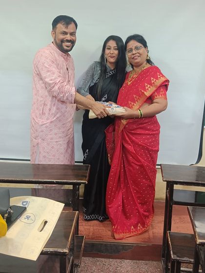 A teacher receives her Diwali gift from Prof. Parab and a senior staff member, all sharing a happy moment.