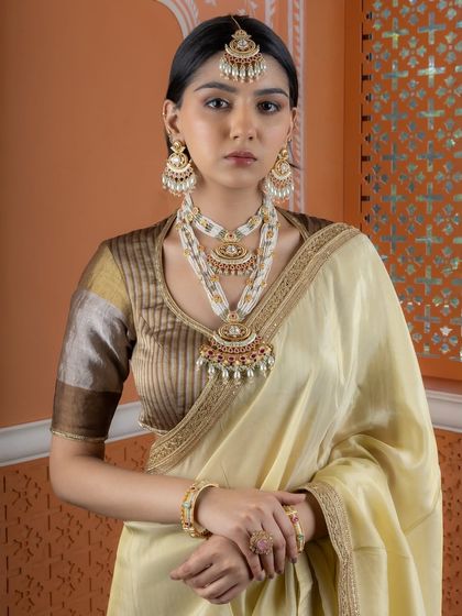 A full-length view of a model wearing the layered Kundan pearl necklace set with a beautiful saree. This demonstrates how our grandest pieces can be styled for a complete, traditional bridal look.