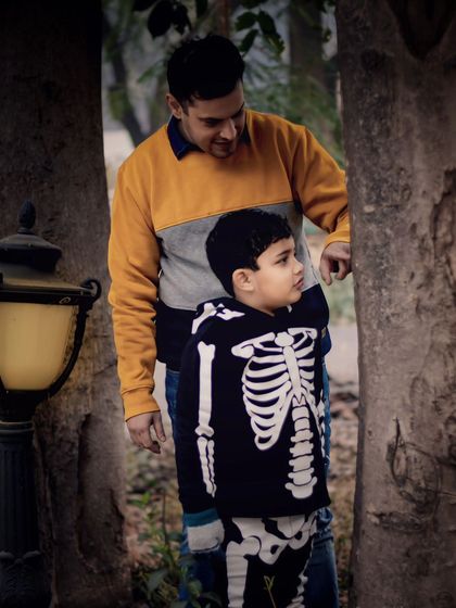 A father and son share a quiet moment of discovery in the park. I love capturing these unposed interactions that reveal the depth of the father-son bond.