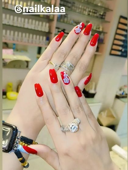 A classic and bold look with vibrant red nails. The accent nails feature delicate, hand-painted white and purple floral designs for an elegant touch.