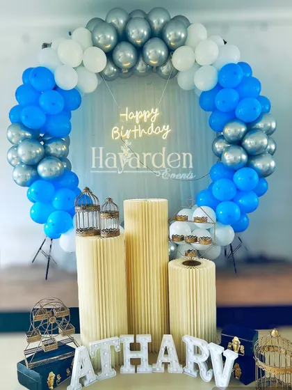 A blue, white, and silver balloon ring setup, complete with pedestals and decorative props like birdcages.