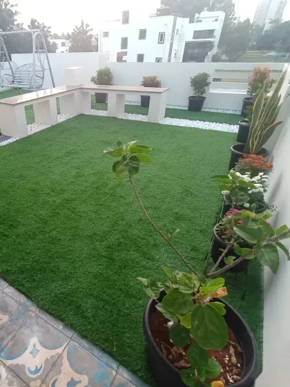 This terrace features artificial grass paired with built-in seating and a variety of potted plants. It shows how you can combine artificial turf with live plants for a beautiful effect.
