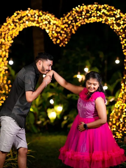 A classic romantic gesture in front of a heart-shaped light installation. Night shoots with creative lighting are my specialty.