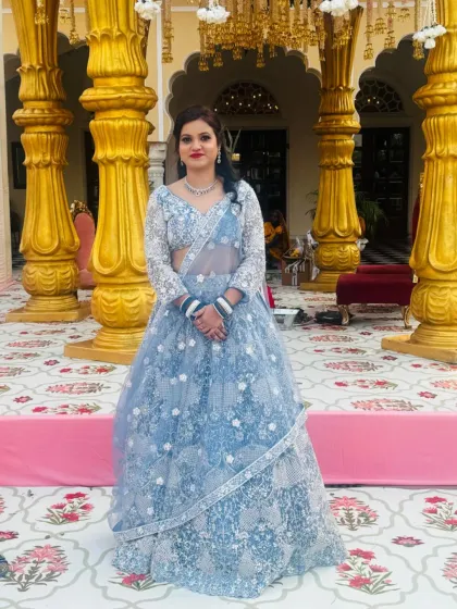 A client wearing a powder blue lehenga with all-over white floral embroidery. The long-sleeved blouse makes it a chic and elegant option.