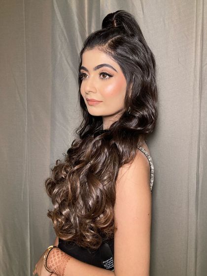 The side profile of this wavy high ponytail shows how it adds volume and frames the face beautifully. A great choice for a sangeet or reception.