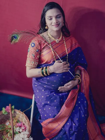 We use simple props like a peacock feather to add a touch of grace and tradition to the photos. This portrait captures the mother's peaceful expression in a beautiful blue and orange saree.