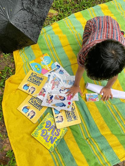 A child explores books and stickers on a mat during our rainy-day Diwali session. Even when we have to move indoors, we ensure there are plenty of hands-on activities.