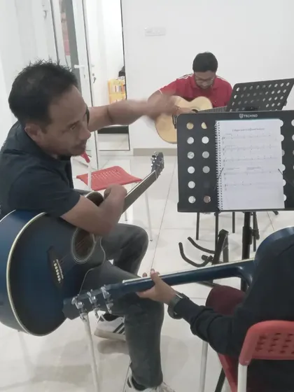 An instructor helps a student with their guitar chords. We make sure every student gets the basics right.