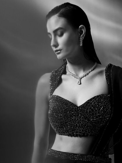 A beautiful black and white portrait of a model wearing an embellished blouse and diamond necklace. The monochrome effect adds a timeless, classic elegance to the image.