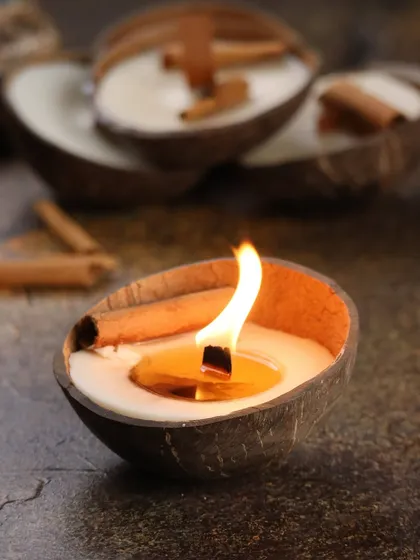 The Cinnamon Coconut Soy Candle, lit and glowing, its wooden wick crackling softly like a tiny fireplace.