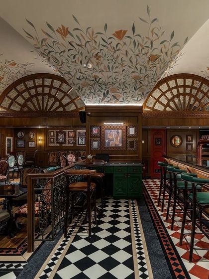 Another view of the pub's interior, showing the intricate ironwork of the balustrade and the rich layering of patterns and materials.