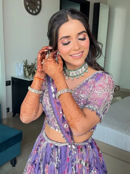 A vision in lilac for a Mehendi ceremony. The hair is styled in a simple half-up twist with soft waves to complement the colorful makeup.