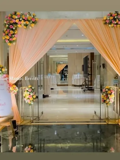 A grand entrance for an engagement party, with peach drapes and beautiful floral arrangements. This design creates a luxurious and welcoming passage into the main event area.