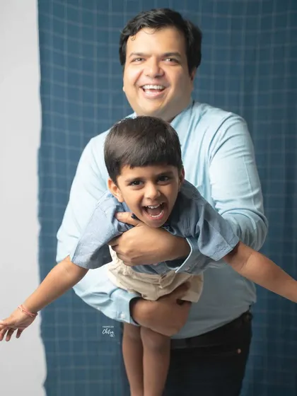 The pure energy and laughter between a father and son. I encourage playful moments like this during my family photoshoots to capture genuine expressions. This candid shot against a simple studio backdrop highlights their joyful connection.