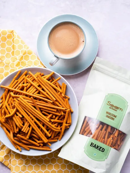 The ultimate tea-time pairing. A cup of chai sits next to a bowl of my baked Tikha Gathiya, creating a cozy and inviting scene.