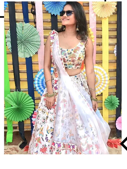 Fun, flirty, and fashionable. Our client is ready for a daytime party in this white lehenga with colorful floral embroidery.